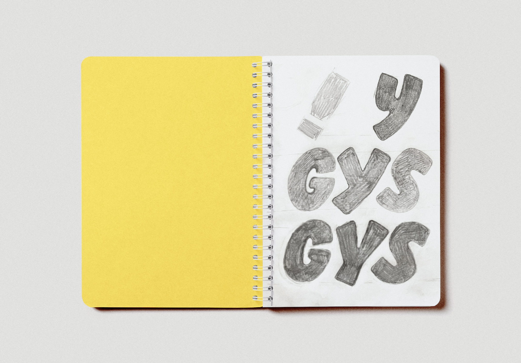 GYSHIDO custom lettering sketches in pencil on notebook showing GYS letterforms and exclamation mark development